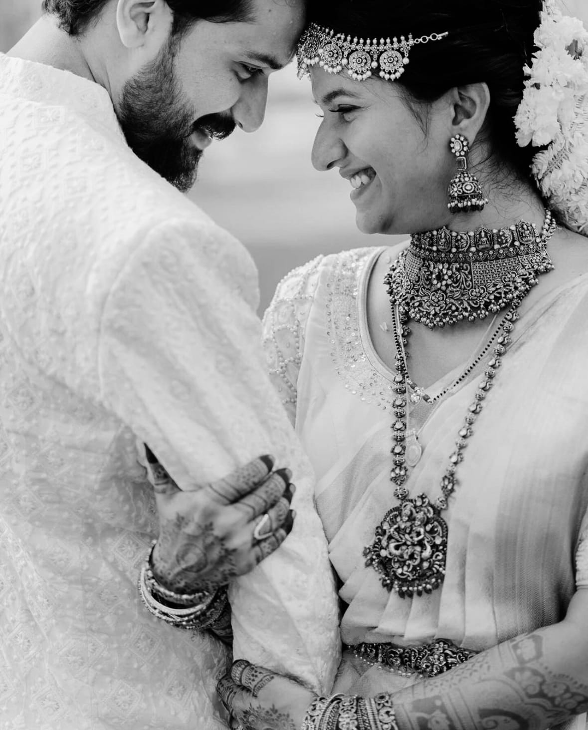 Couple in white and silver temple jewellery, laughing forehead to forehead