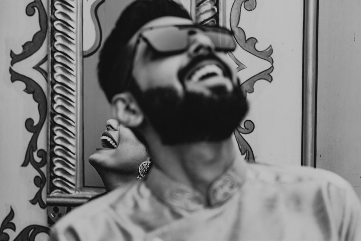 He throws his head back laughing against a carved doorway while she laughs into his shoulder