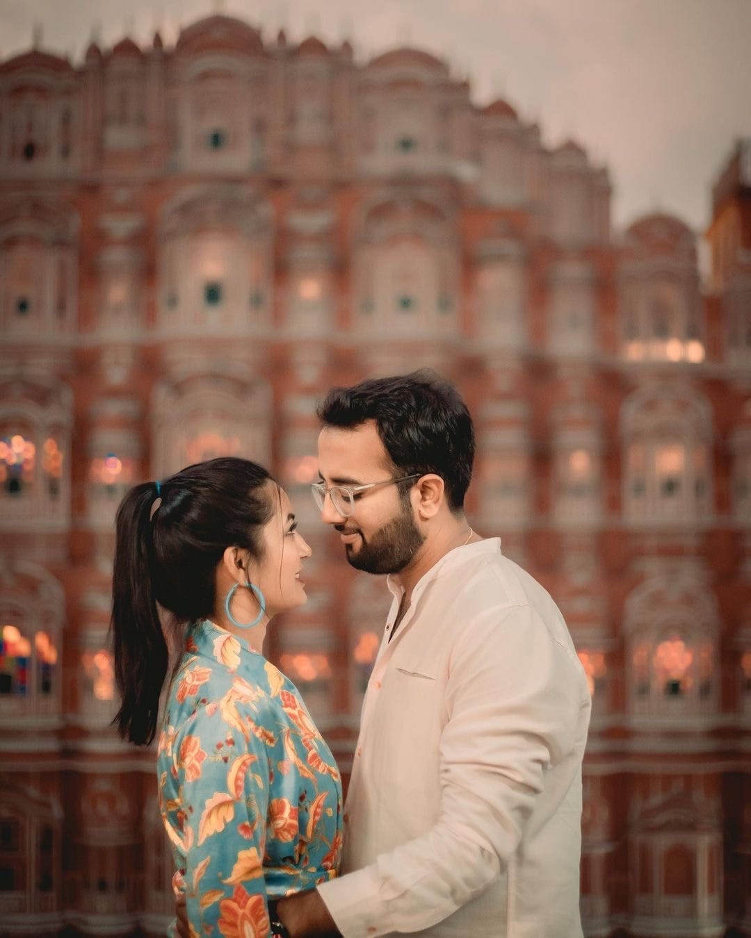 Couple standing forehead to forehead in front of the lit facade of Hawa Mahal in Jaipur