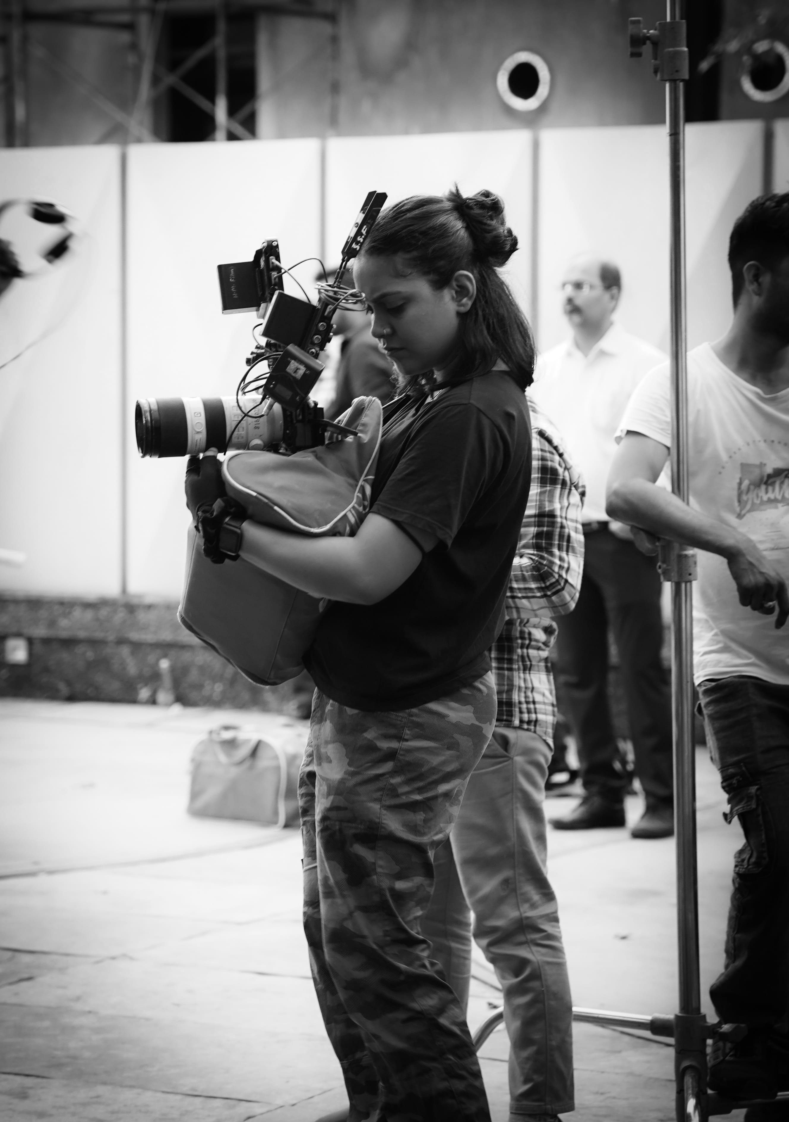 Tanya Sristy on set in black and white, holding a rigged cinema camera against her shoulder
