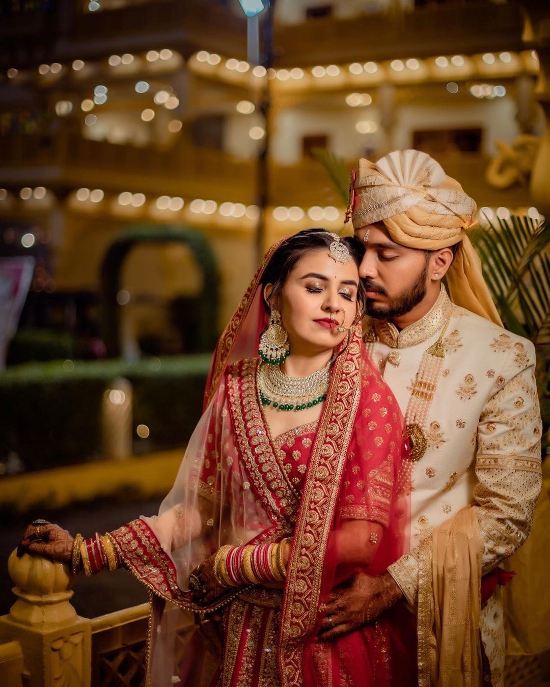 Groom rests his forehead against the bride's under a courtyard strung with warm lights